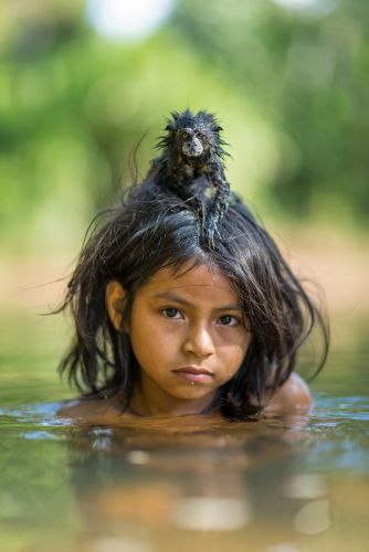 Menina e seu Macaquinho de estimação, banhando-se no Parque Nacional de Manú, no Peru