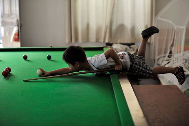 Wang Wuka, debruçado sobre a mesa enquanto faz uma jogada